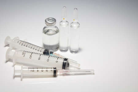 Medical syringe and vials on white table