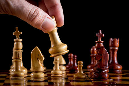 Hand playing wood chess on black backgroundの写真素材