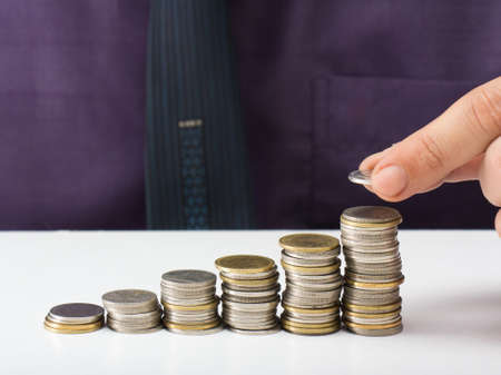 Businessman fill a coin into heap stairの写真素材