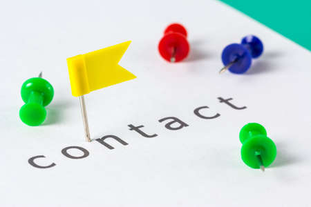 Flag push pin on paper at contact word
