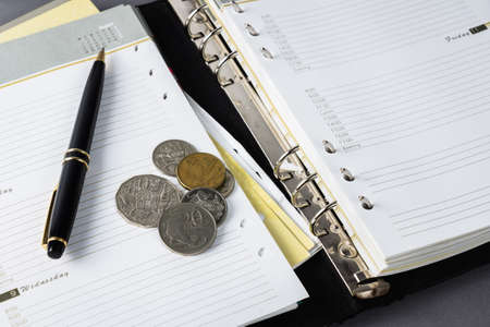 Coins and pen on schedule page in organizer