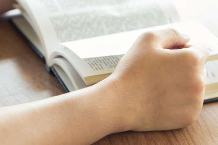 Closeup hand holding  page of book for reading
