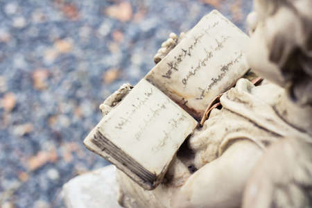 Closeup book in hand of old cupid's statueの写真素材