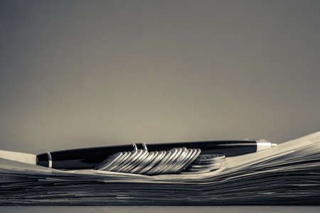 Coins and pen on pile of receiptsの写真素材