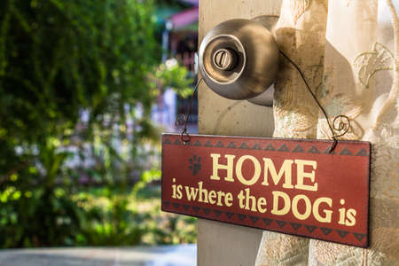 A sign "Home is where the dog is" hanged at the door knobの写真素材