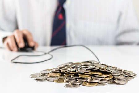 Pile of coins with hand on computer mouse, businessman can manage personal finance directly and...