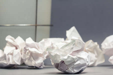 Crumble paper balls on gray ground with part of bin