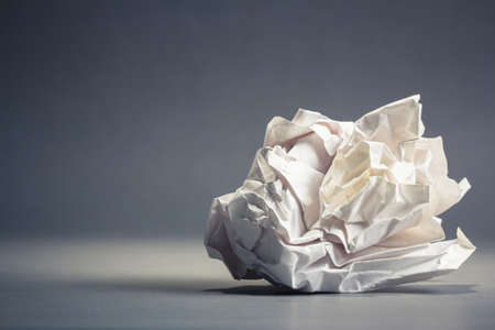 Single crumble paper ball on gray ground with copy spaceの写真素材