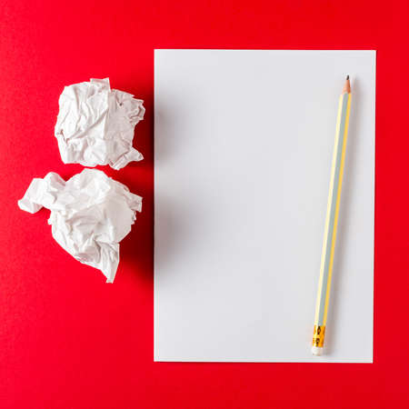 Paper on red background with pencil and crumble paper balls