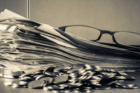Receipts binding in paper nail with eyeglasses and pile of coins