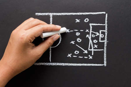 Hand drawing a soccer strategy chart with chalk