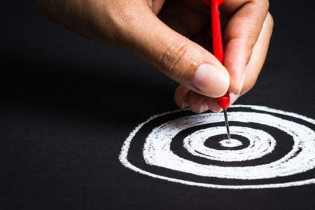Setting goal or accurate planning, hand going to take dart into the center of sketching dartboardの写真素材