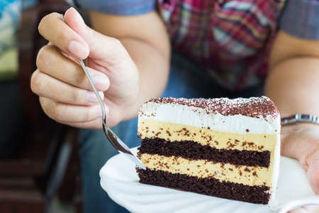 Butter and caramel cake with chocolate chips topping in womanの写真素材