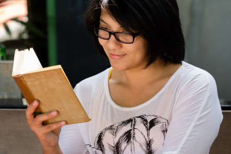 Woman in casual clothes reading old book and smiling