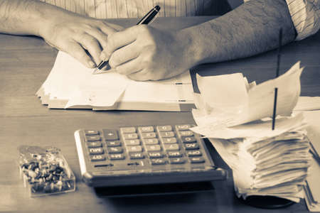Closeup man working with receipts on wood tableの写真素材