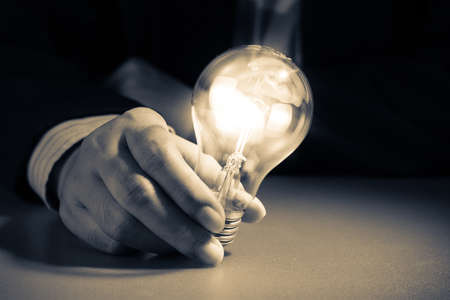 Businessman hold glowing light bulb in the darknessの写真素材