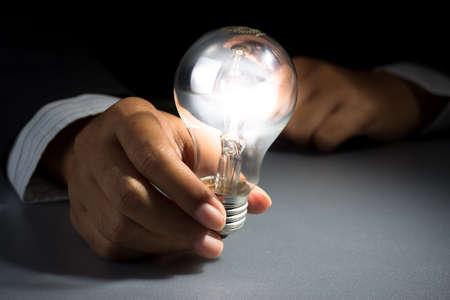 Businessman hold glowing light bulb in the darknessの写真素材