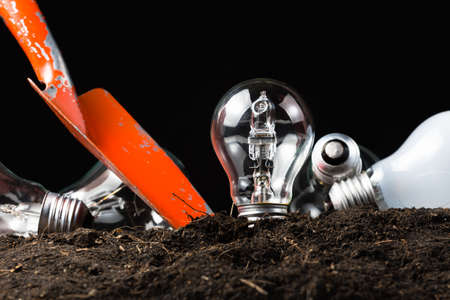 Light bulb as idea symbol in soil with shovel to digの写真素材