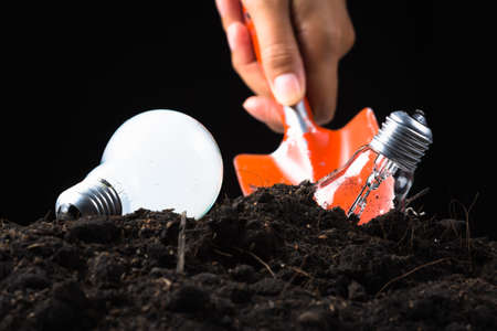 Hand use shovel to dig and collect light bulb in soilの写真素材