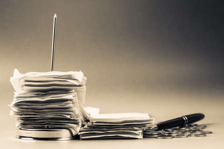 Pile of receipts in paper nail with coins and pen for financial or tax concept