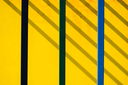 Abstract building, color metal post on concrete wall with shadow lines