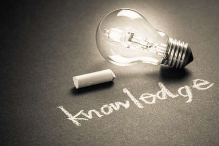 Handwriting of Knowledge word with chalk and glowing light bulb