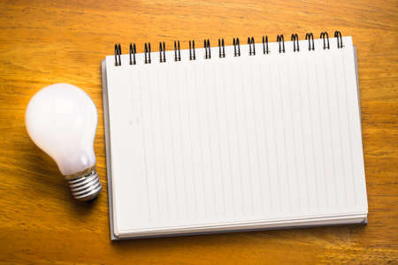 Spiral notebook with light bulb on wood backgroundの写真素材