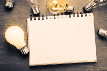 Spiral notebook with light bulbs on wood backgroundの写真素材