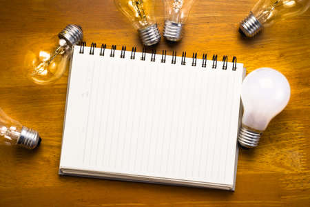 Spiral notebook with light bulbs on wood backgroundの写真素材