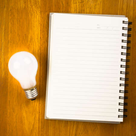Spiral notebook with light bulb on wood backgroundの写真素材