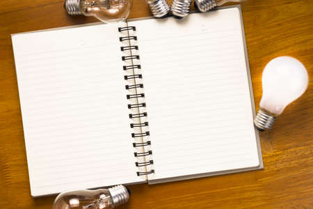 Spiral notebook with light bulbs on wood backgroundの写真素材