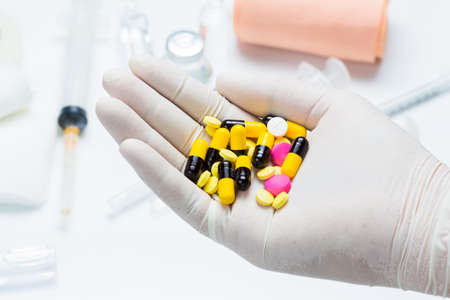 Hand in rubber glove with medicine pillsの写真素材