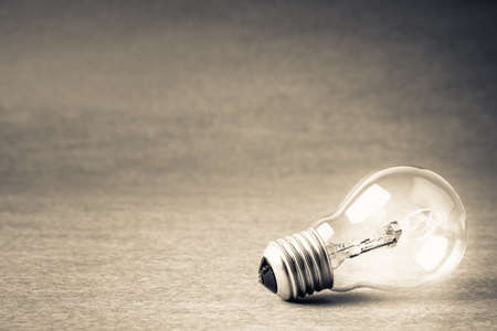 One light bulb glowing on gray paperの写真素材