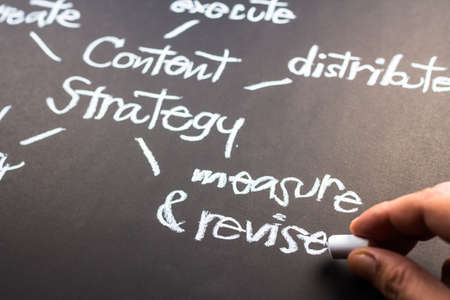 Hand writing Content Strategy concept on black paperの写真素材