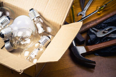 Many light bulbs in cardboard box with tools