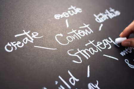Hand writing Content Strategy concept on black paperの写真素材