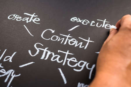 Hand writing Content Strategy concept on black paperの写真素材