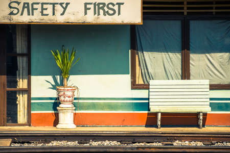 Old building with bench beside the railway with Safety First sign, train station in Thailandの写真素材