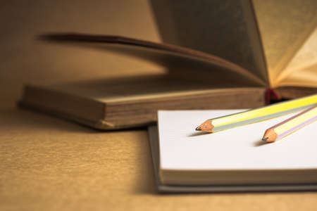 Pencils on notebook with old opened bookの写真素材