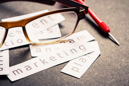 Marketing plan word printed on pieces of paper with eyeglasses and dartの写真素材