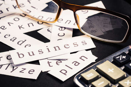 Business plan word printed on pieces of paper with eyeglasses and calculatorの写真素材