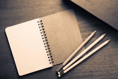 Opened spiral notebook with pencils on wood table