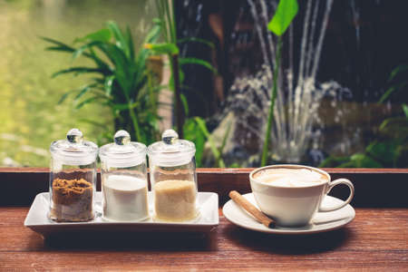 Cappuccino with sugar bottles on wood balcony in the gardenの写真素材