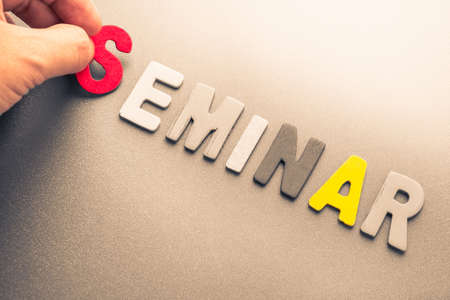 Hand arrange wood letters as Seminar word