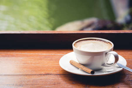 Cappuccino on wood balcony beside the pond on backgroundの写真素材