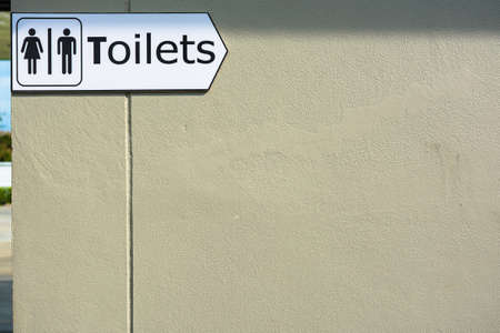 Toilet direction sign on brown wallの写真素材