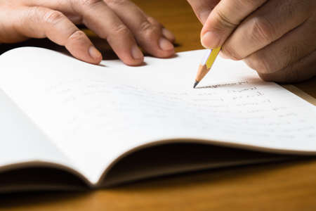 Closeup hand writing on notebook with pencil