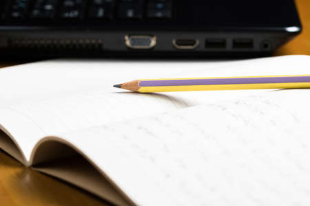 Closeup pencil on notebook with laptop, writing for communication conceptの写真素材