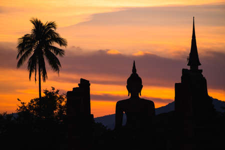 Silhouette Buddha statue and pagoda with beautiful clouds in Sukhothai Historical Parkの写真素材