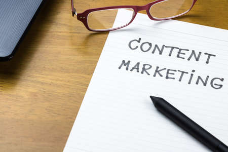 Handwriting of Content Marketing topic on paper with part of laptopの写真素材